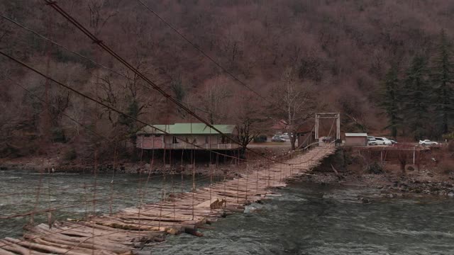 一座古老的悬索桥横跨山间河流，俯瞰一座废弃的桥，d- cinlike，没有颜色分级视频素材