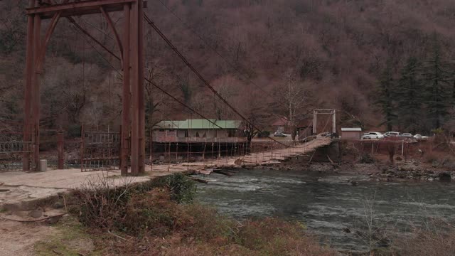 一座古老的悬索桥横跨山间河流，俯瞰一座废弃的桥，d- cinlike，没有颜色分级视频素材