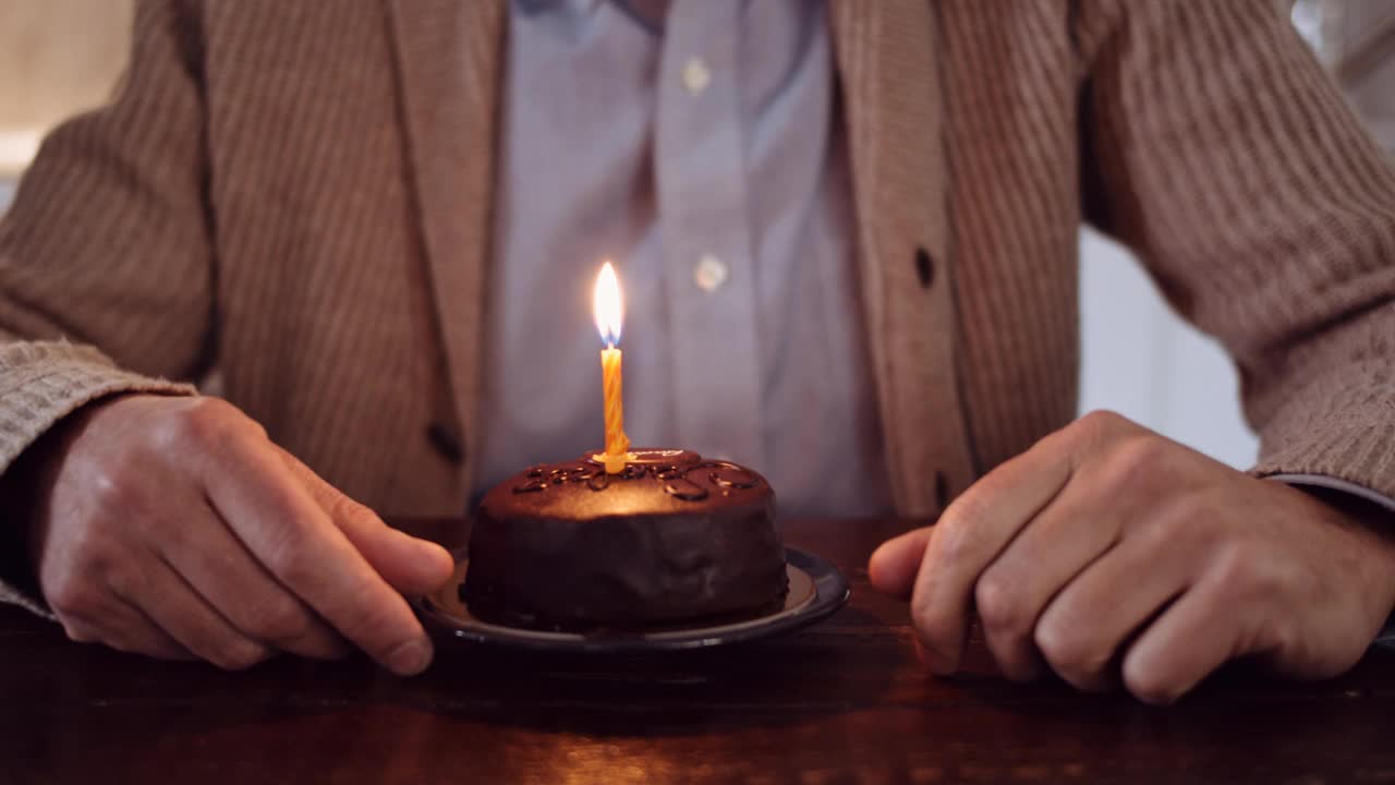 一个成熟男人吹灭生日蛋糕上的蜡烛的慢镜头视频素材