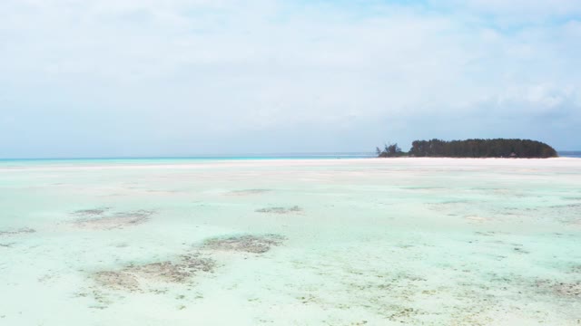 在坦桑尼亚桑给巴尔岛附近的印度洋上，无人机在蒙尼巴岛周围的浅层环礁海浪中飞行。异国旅行概念4K镜头。视频素材