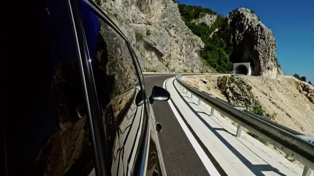 现代汽车骑在柏油路附近的山，然后进入隧道期间旅行，在黑山农村晴朗的一天视频素材