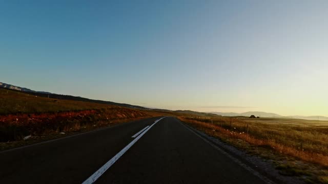 在日落时穿过田野的公路旅行视频素材