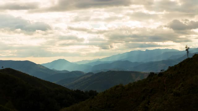 在泰国南怀Thon村，阳光透过云层出现在山景中的时间流逝视图。镜头时间推移的自然景观和戏剧性的彩色天空。视频素材