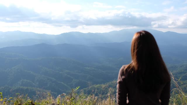 一个女性旅行者的后视图看一个美丽的绿色山景视频素材