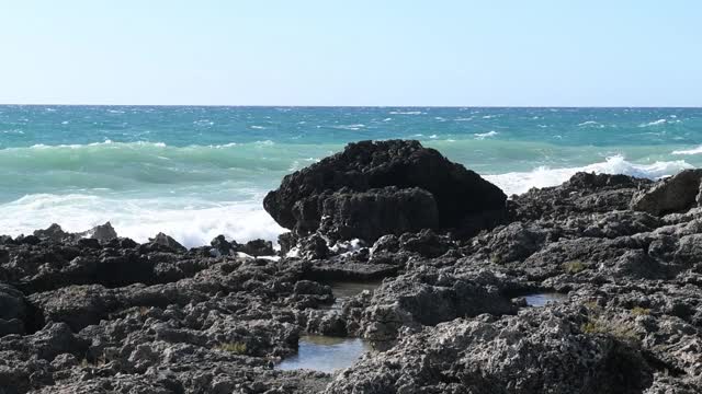 在意大利普利亚旅游胜地，海浪冲击着黑色的岩石视频素材