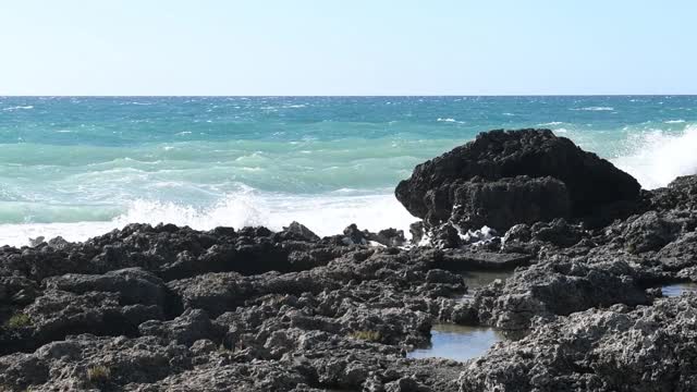 在意大利普利亚旅游胜地，海浪冲击着黑色的岩石视频素材