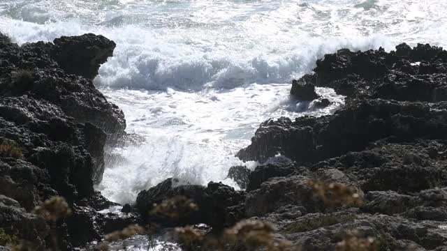 在意大利普利亚旅游胜地，海浪冲击着黑色的岩石视频素材