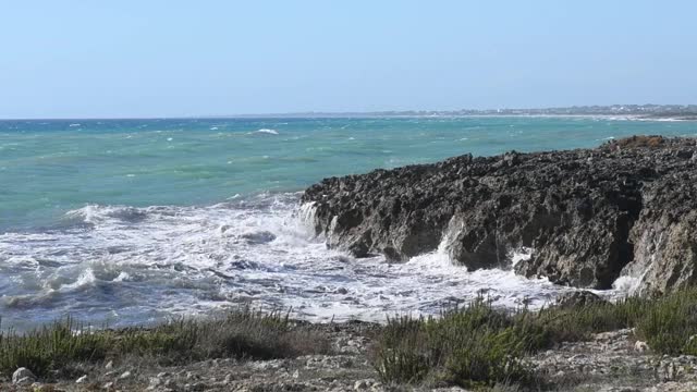 在普利亚，意大利海岸的黑色岩石的海浪冲击全景视频素材