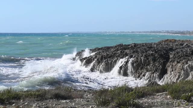 在普利亚，意大利海岸的黑色岩石的海浪冲击全景视频素材