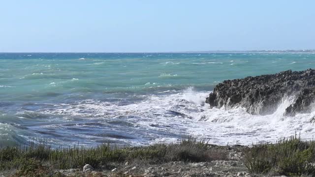 在普利亚，意大利海岸的黑色岩石的海浪冲击全景视频素材