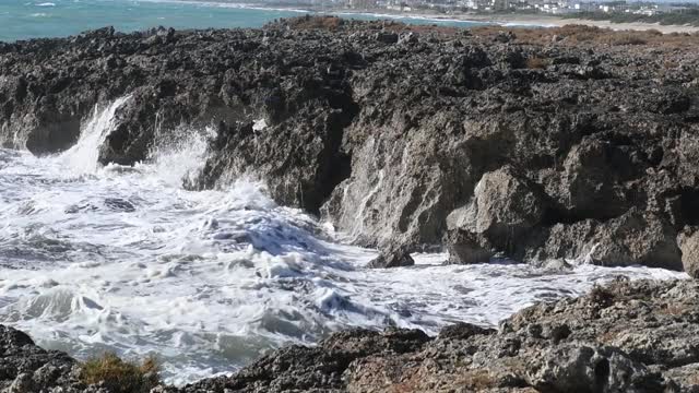 在意大利普利亚旅游胜地，海浪冲击着黑色的岩石视频素材