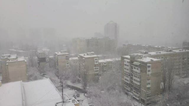 慢镜头透过窗户拍摄城市里的暴风雪视频素材