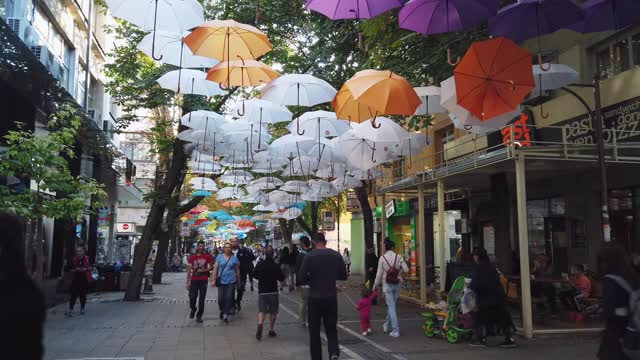 人们走在装饰着五颜六色雨伞的街道上视频素材