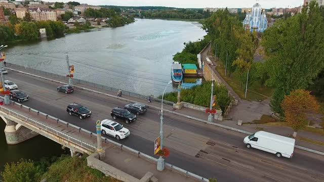 桥与汽车的城市景观。桥上行驶的汽车。镇上河边绿色公园的全景。无人机鸟瞰图。视频素材