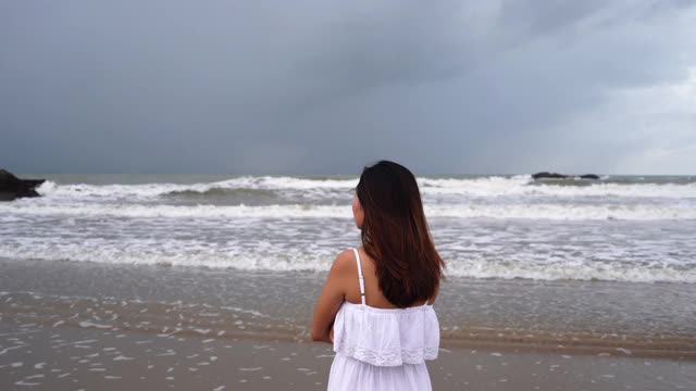 一个年轻女子在阴沉的日子里望着大海，感到孤独和悲伤视频素材