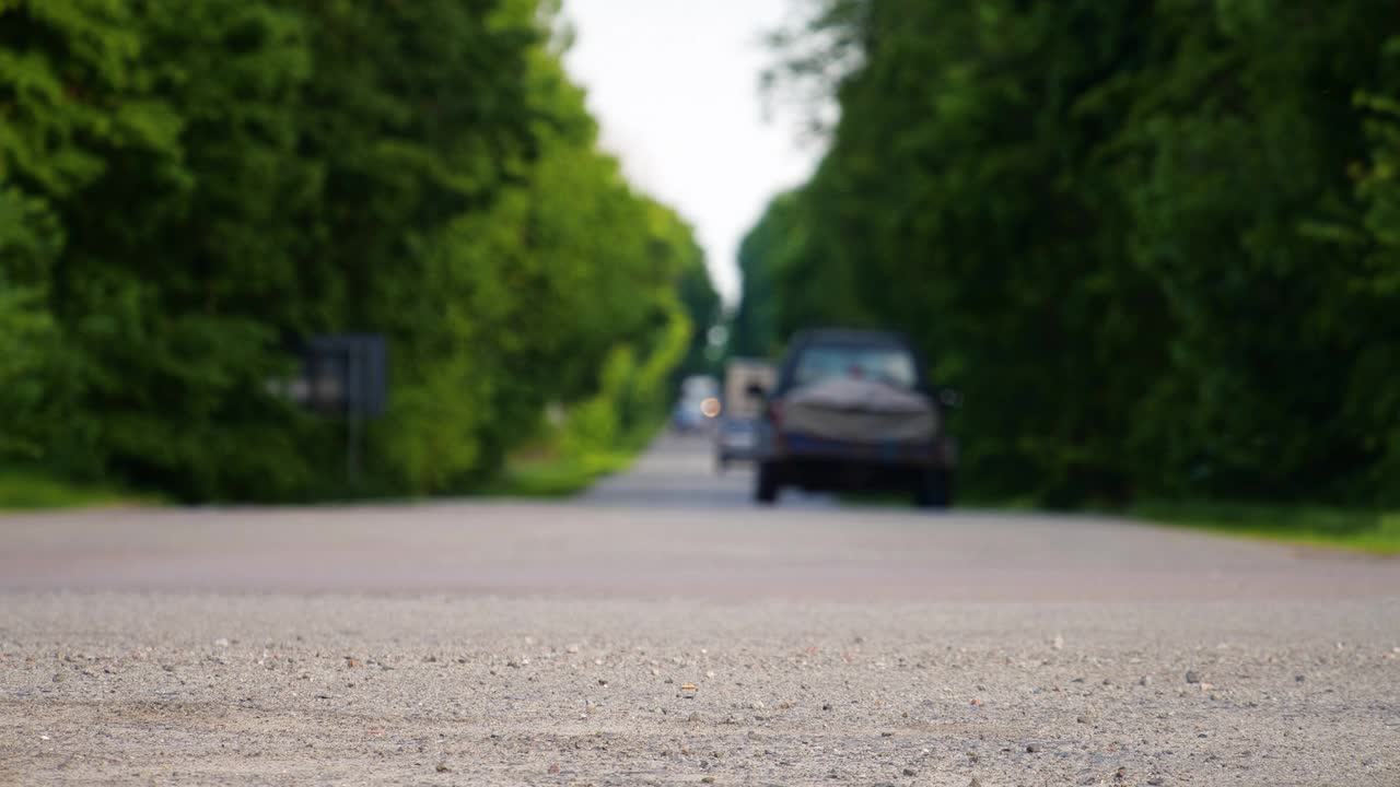 汽车行驶在乡村的道路上，失去焦点，4k的背景，城市外的土路，树木之间美丽的道路视频素材