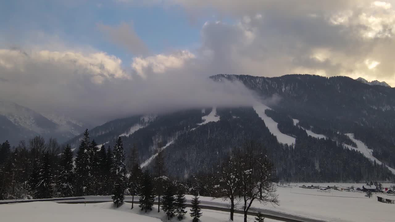 日落时，白雪皑皑的山峰覆盖着森林和云彩。无人机视频视频素材