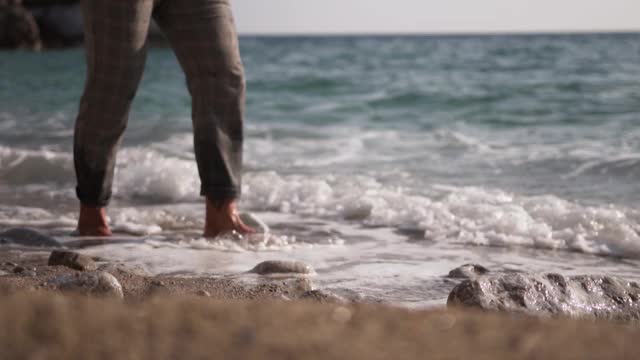 在海滩上散步的人。海浪碰到了他的脚视频下载