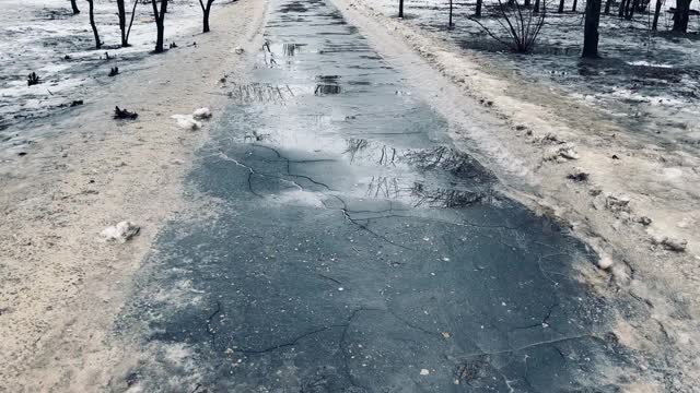 在春天的时候，人行道上有水坑。被融化的积雪和肮脏的积雪摧毁的道路视频素材