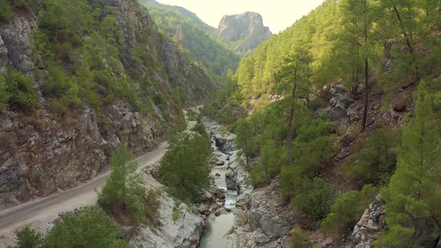 蜿蜒的道路沿着河流和土耳其山区峡谷的针叶林。鸟瞰图4 k。视频素材