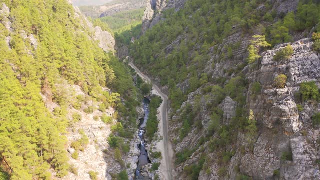 一名男子站在一辆汽车旁的道路上，一个野生的山峡与一条河在土耳其。鸟瞰图4 k。视频素材