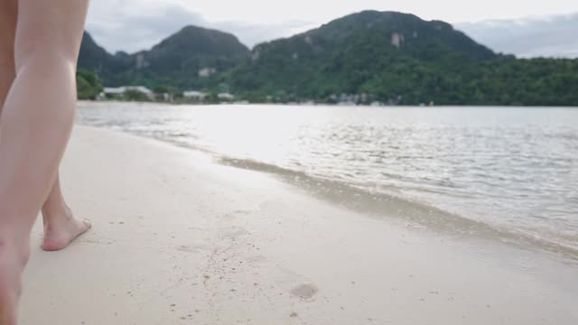 低角女沿空岛沙滩岸边散步，阳光反射在海水上，自由生活逃离城市，暑假慢动作，平静祥和的暑假视频素材