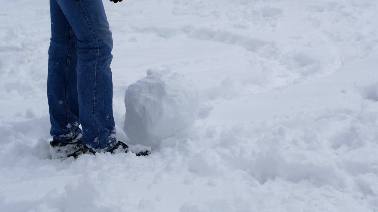 一个男人走在白雪上，雕刻了一个巨大的雪花玻璃球。近距离拍摄下雪的天气和在雪中行走。视频素材