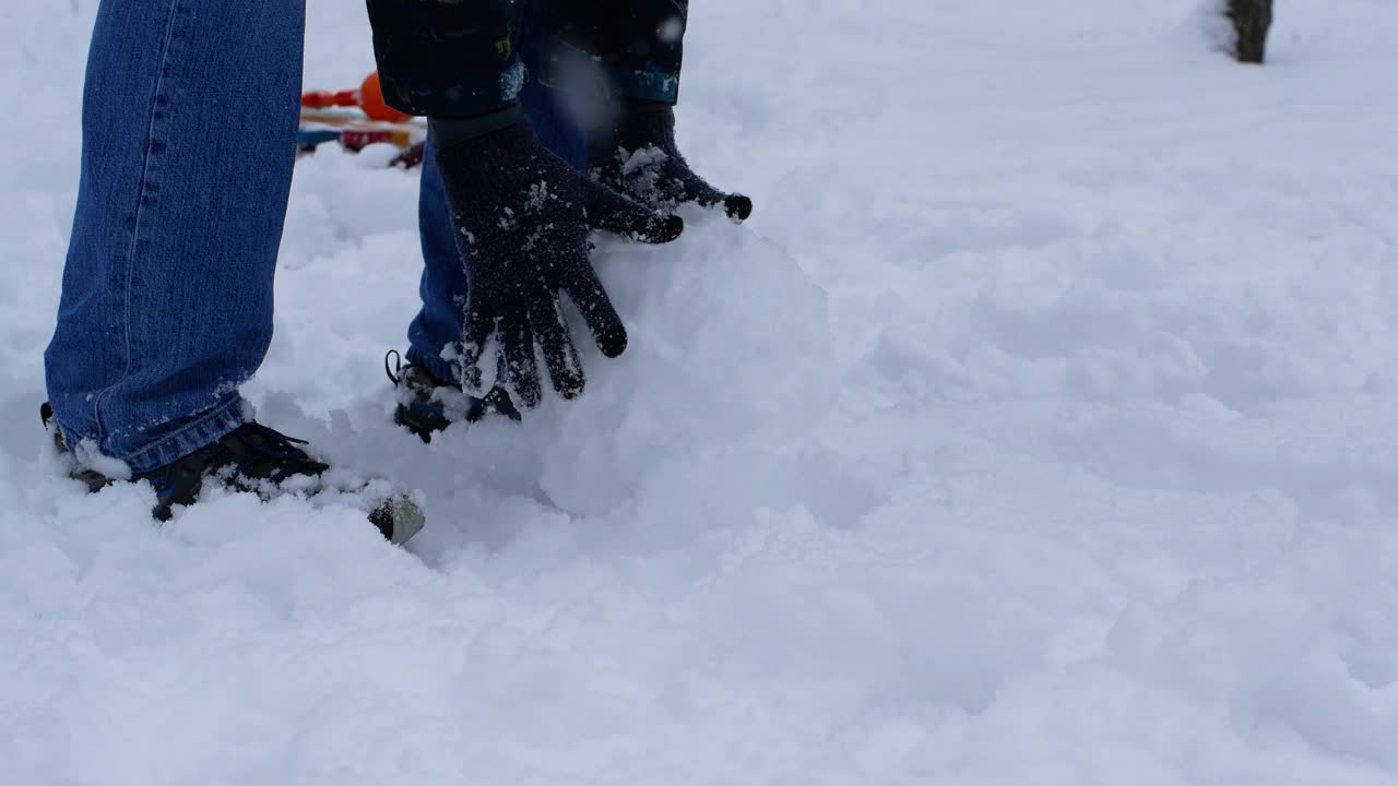 一个男人走在白雪上，雕刻了一个巨大的雪花玻璃球。近距离拍摄下雪的天气和在雪中行走。视频素材