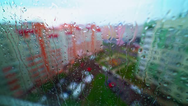 大雨在户外。从室内透过潮湿的窗户观看城市建筑。雨滴落在玻璃窗上。视频素材