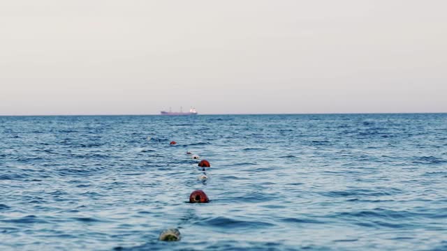 海水背景带浮标区。这艘船漂在大海的远处。湛蓝的海水在晚上的晴空下。视频素材