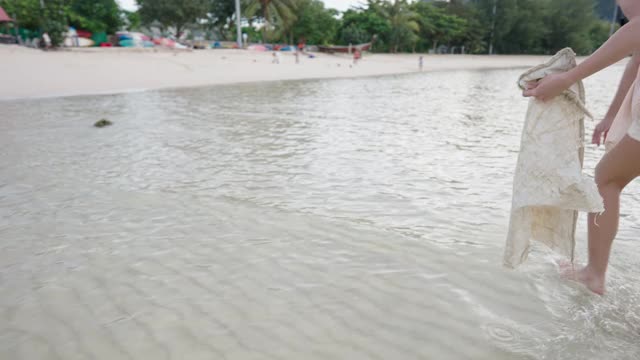 亚洲年轻女性从海边岛屿海滩收集塑料袋旅行，收集垃圾志愿垃圾塑料垃圾瓶子。生态环保意识，垃圾水污染视频素材