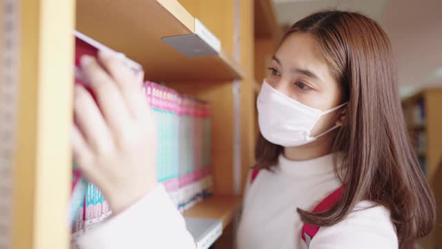 女学生们在大学图书馆的书架上寻找书籍。视频素材