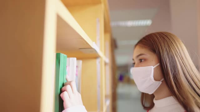 女学生们在大学图书馆的书架上寻找书籍。视频素材