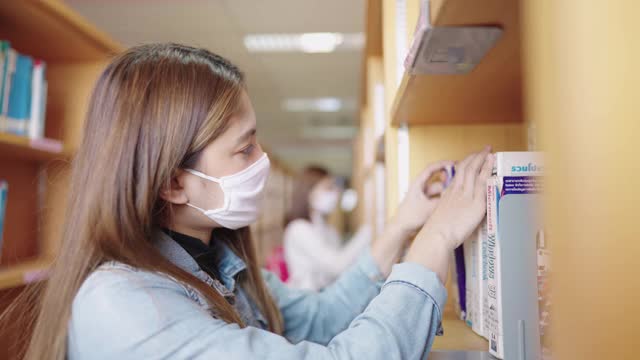 女学生们在大学图书馆的书架上寻找书籍。视频素材