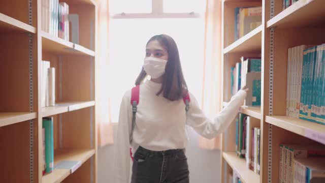 女学生们在大学图书馆的书架上寻找书籍。视频素材