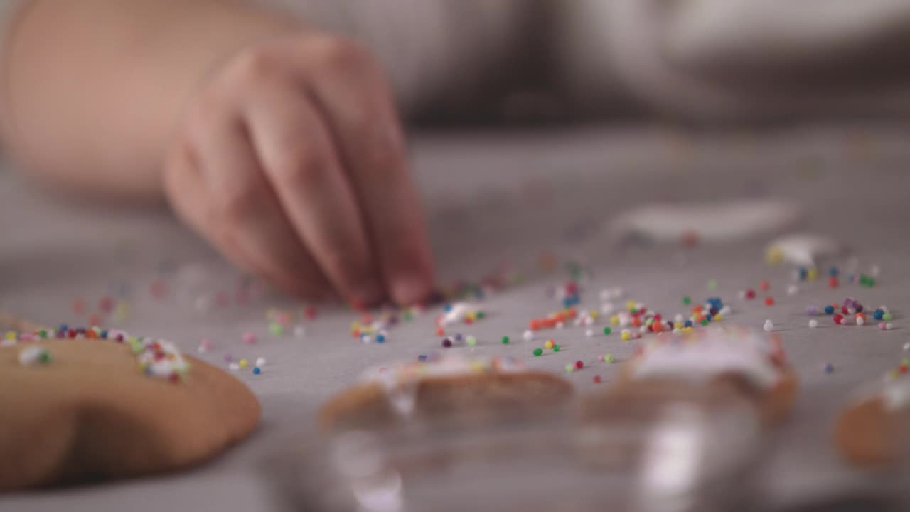 小女孩正在装饰姜饼，她正在收集糖屑，撒在饼干上视频素材