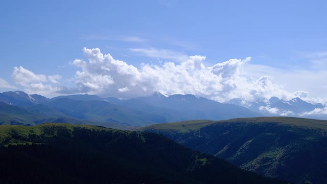 美丽的绿色山脉在蓝色多云的天空背景。乡村景观、自然。自然场景。美丽的Zaili-Alatau山脉，拍摄自Assy高原。视频下载