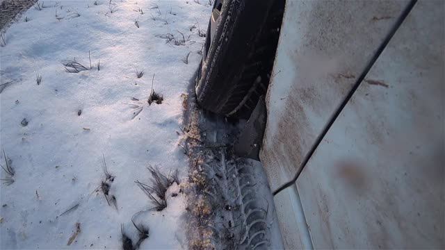 肮脏的白色车轮旋转，吐出了沉重的湿雪，司机试图在具有挑战性的冬季条件下驾驶道路和沼泽飞溅相机镜头视频素材