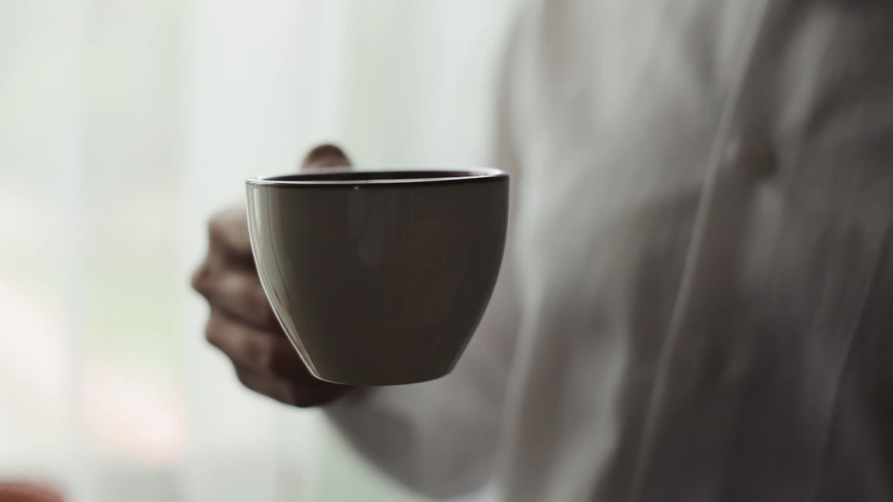 近距离观看男子喝着热腾腾的咖啡或茶，享受着美丽的早晨感觉快乐视频素材