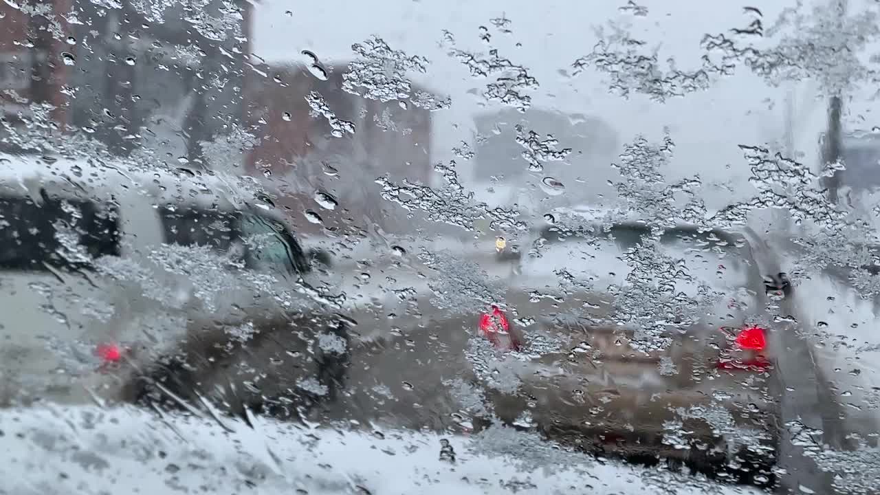 雨夹雪落在车窗上，背景是城市和汽车视频下载