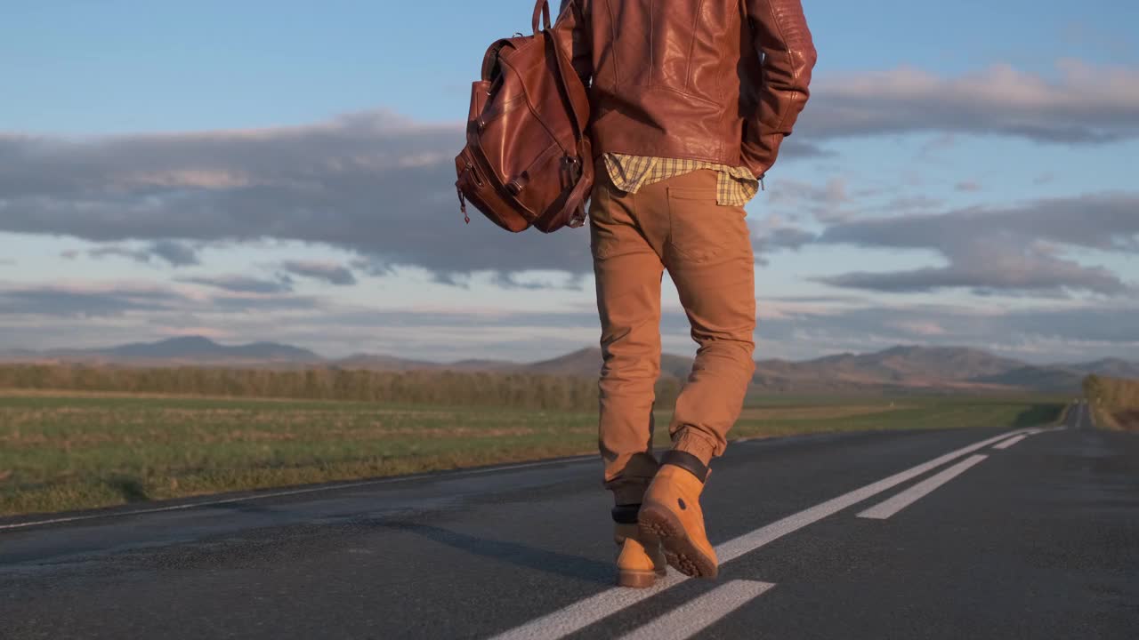 潮人搭车旅行者旅行者背着背包走在漫长的道路上视频素材