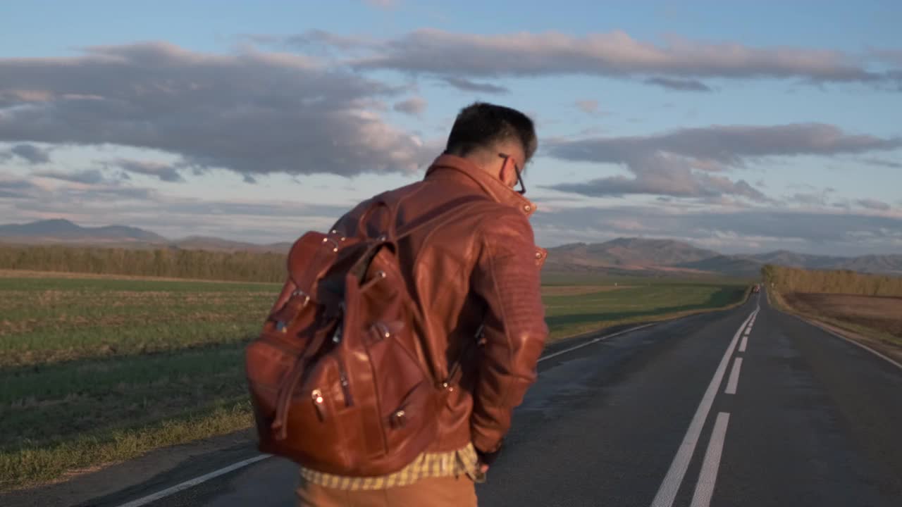 潮人搭车旅行者旅行者背着背包走在漫长的道路上视频素材