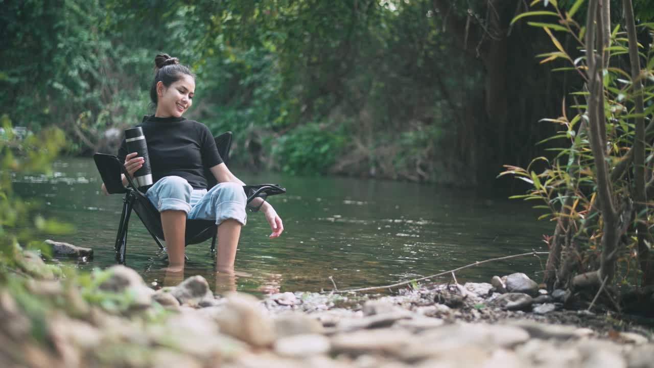 一位年轻女子坐在湖里享受大自然。休闲旅游的概念。视频素材