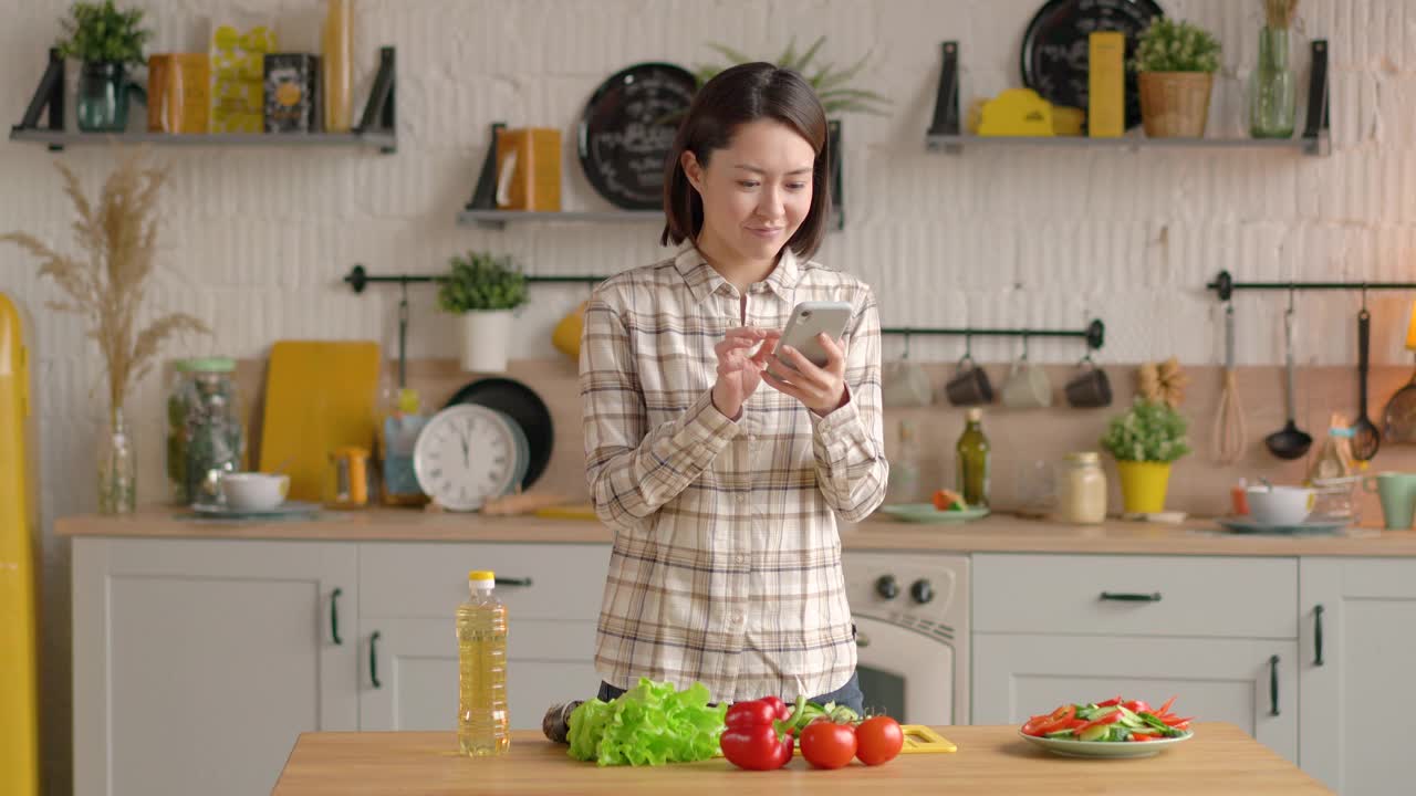 惊奇快乐的多族裔亚洲妇女庆祝得到电子商务购物优惠智能手机在家里。兴奋的混合比赛客户获胜者看手机使用应用程序庆祝移动胜利视频素材