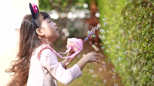 小女孩在家里的花园里玩泡泡视频素材