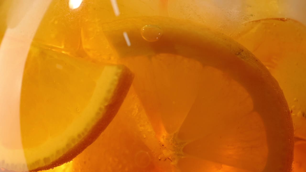 慢镜头近景的转变与冰块和水果片的橙aperol喷鸡尾酒杯视频素材