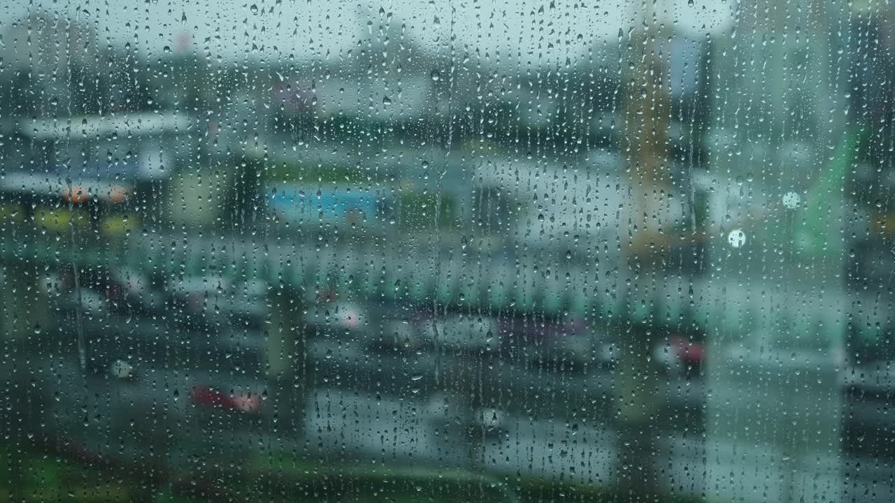 雨点落在窗户玻璃上，雨点落在窗户玻璃上，近距离的水滴下落。在一个下雨和悲伤的流行病日，一件衬衫汽车交通的背景。视频素材