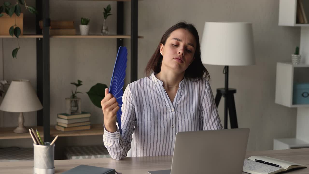 不快乐的年轻女人感觉在现代办公室过热。视频素材