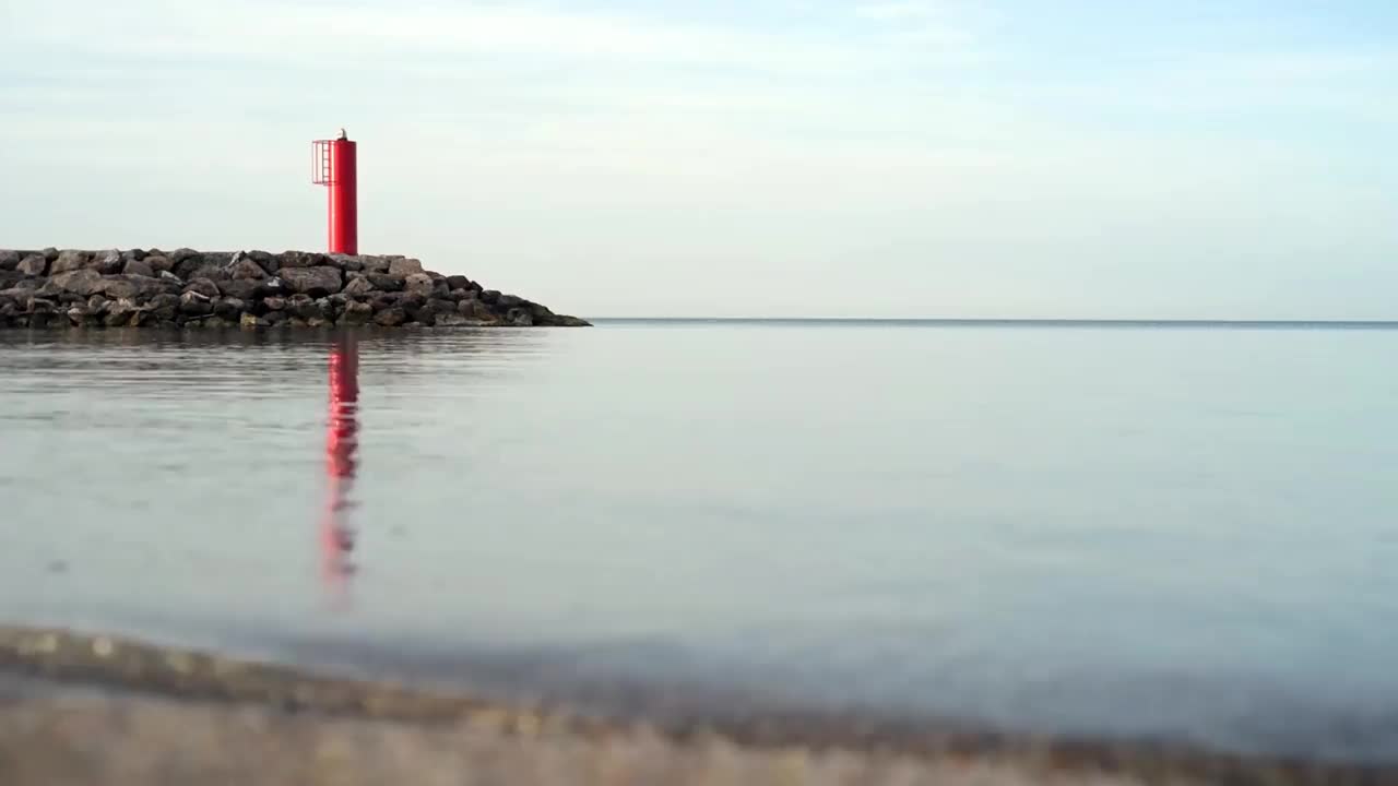 海滩平静的水面反射出一座红色的灯塔视频素材