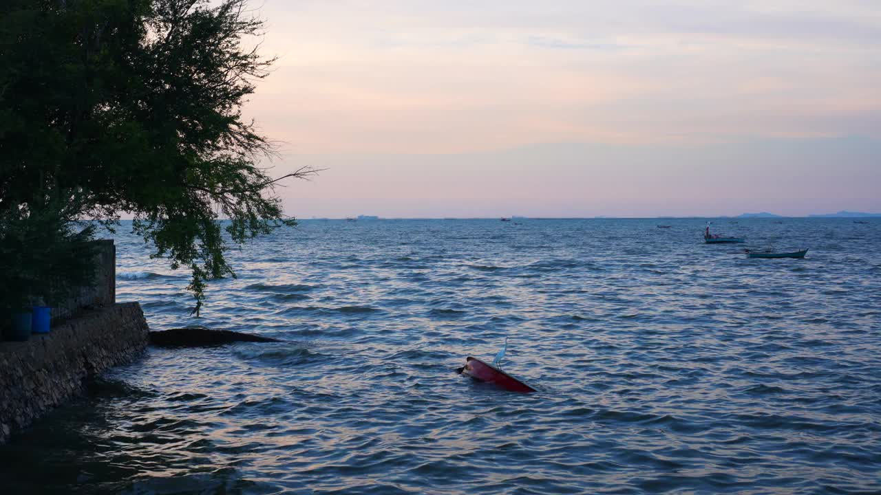 华欣泰海黄昏时分海浪和当地码头上的小船视频素材